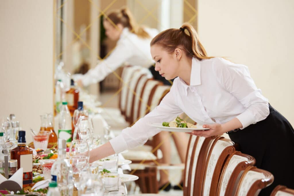Two banquet servers set a table, representing the Atkinson Resort and Country Club tip pooling lawsuit settlement.