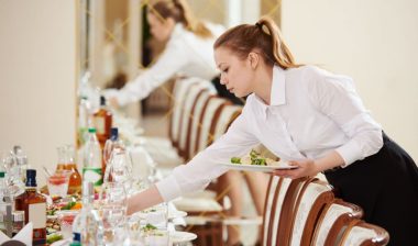 2 Banquet Servers setting a table representing the Atkinson Resort settlement.