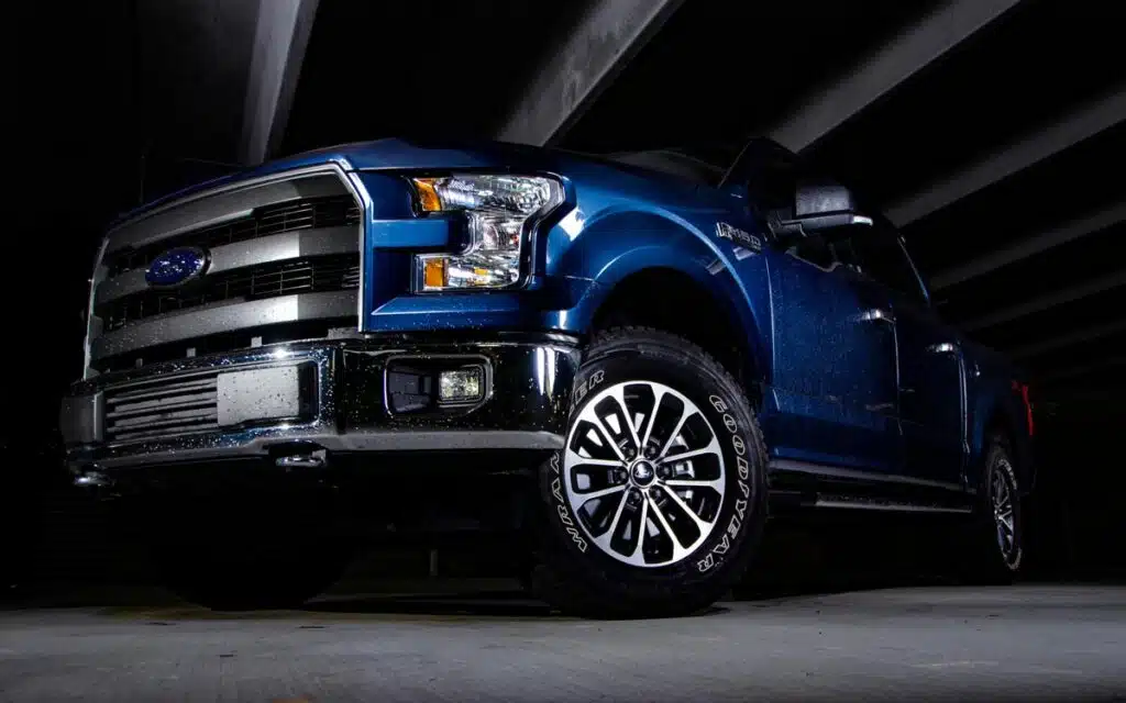 Ford F150 isolated by light with black background in parking garage.