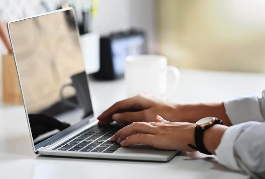 Close up of a womans hands using a laptop.