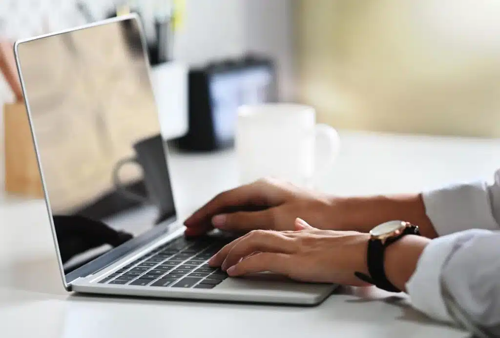 Close up of a womans hands using a laptop.