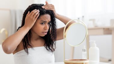 Upset African American Female Looking To Mirror At Her Hair Roots