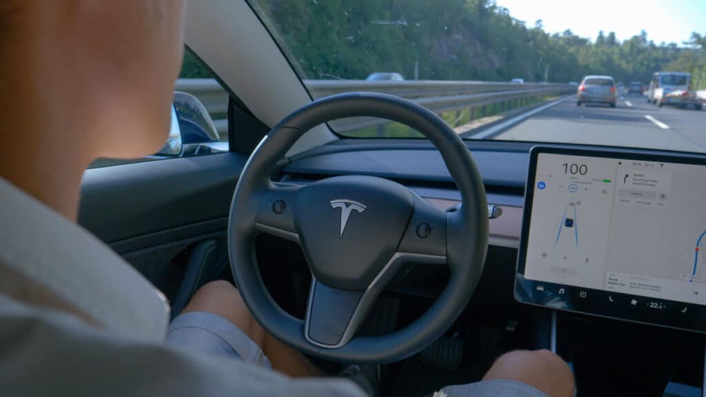 Inside look of the driver side of a Tesla, representing the company pausing its Full Self-Driving beta installations.