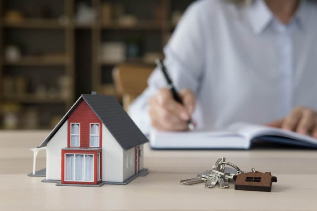 Keys from new home and tiny model of family house on work table of realtor, agent, developer, representing the Build Realty house flipping class action