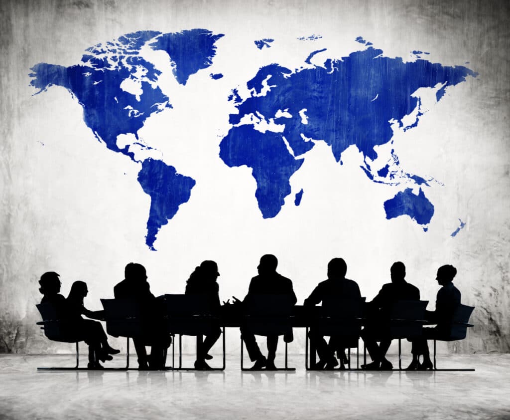 A group of people sitting in a circle with a world map behind them.