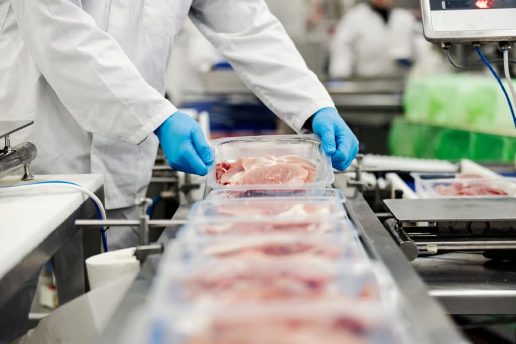 Factory worker and chicken on conveyor belt.