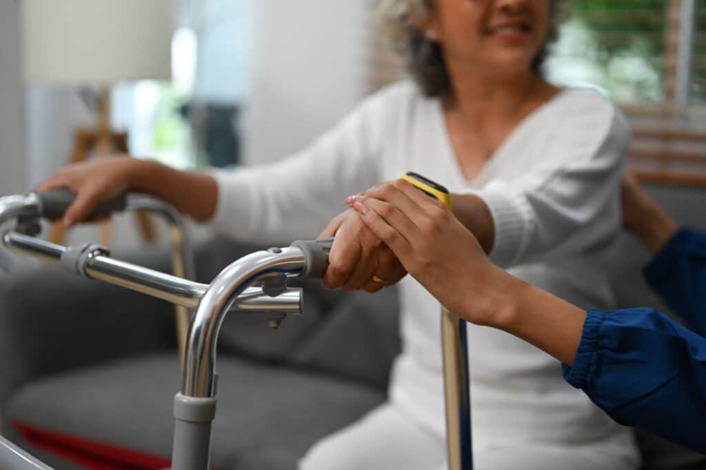 Elderly woman being assisted as she uses her walker representing the Salmon Health fees settlement.
