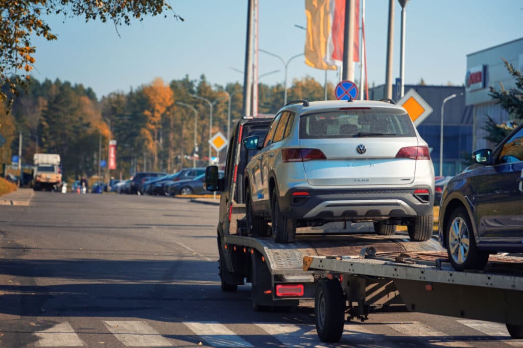Car carrier hauling new VW Taos to car dealership.