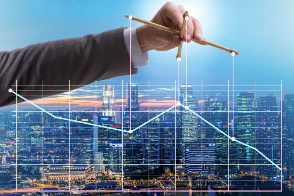 The hand of a man in a business suit holds up a line graph like a puppet to represent ant-trust laws, fines.