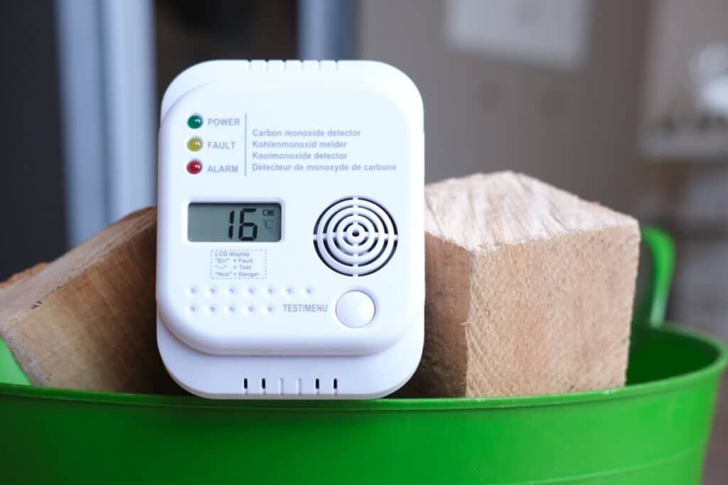 Detail shot of a carbon monoxide alarm or CO warning device in a basket of firewood