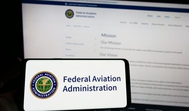 Person holding smartphone with seal of US Federal Aviation Administration (FAA) on screen in front of website representing the FAA air traffic controller EEOC settlement.