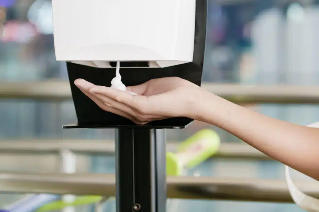 A person using an automatic hand sanitizer machine