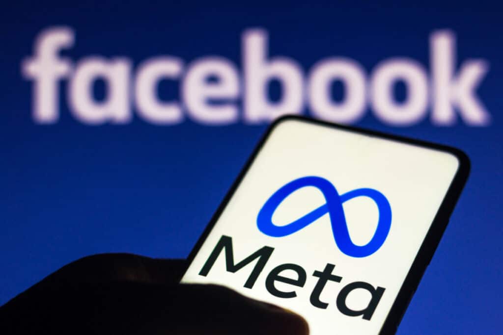 Meta logo seen displayed on a smartphone and in the background the Facebook logo