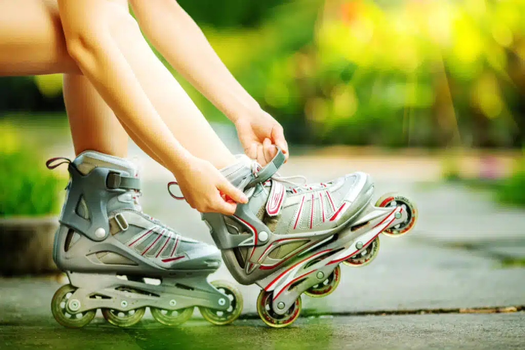 Woman is going rollerblading. Sitting on a bench in a park and putting on inline skates, representing the rollerblade recall.