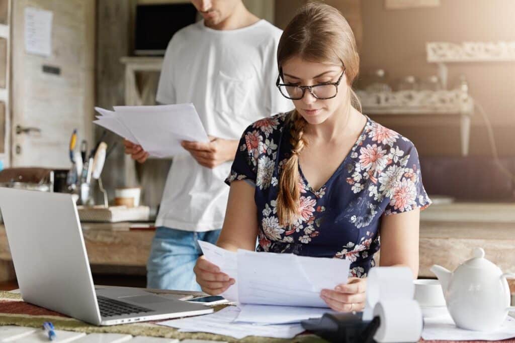 A young couple looking at foreclosure paperwork, representing the Michigan county tax foreclosure class action lawsuit settlement.