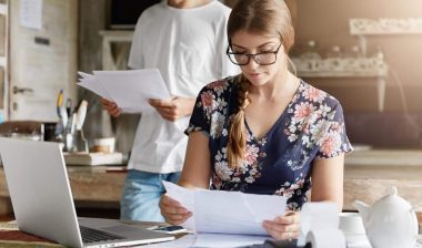 A young couple looking at foreclosure paperwork, representing the Michigan county tax foreclosure settlement.
