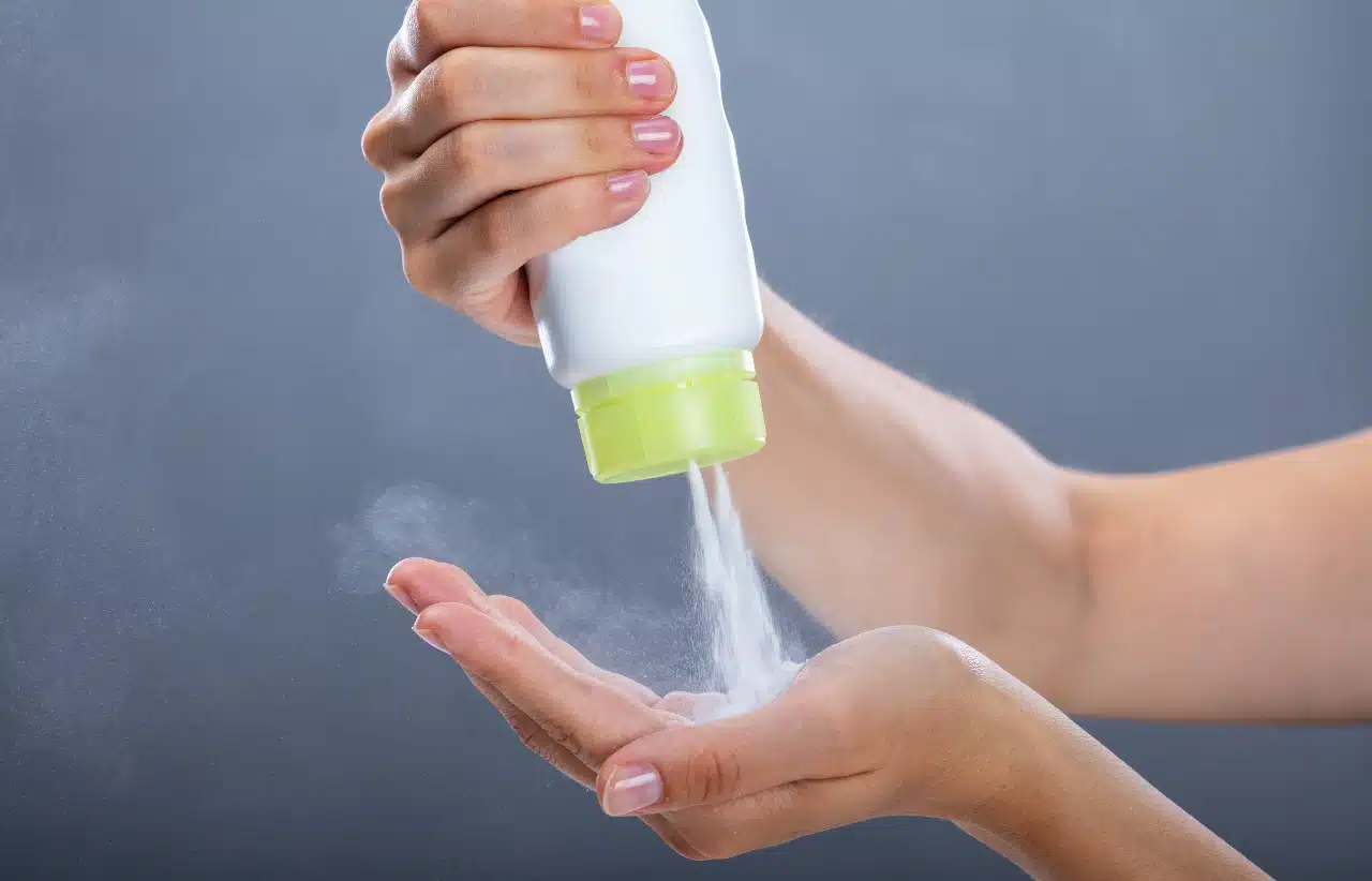 Woman's Hand Using Talcum Powder On Grey Background,
