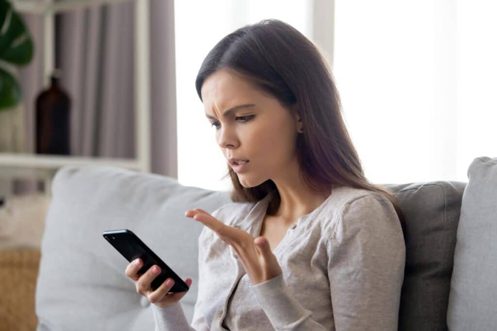Irritated woman looking at her phone, representing the Shark Bar TCPA class action settlement.