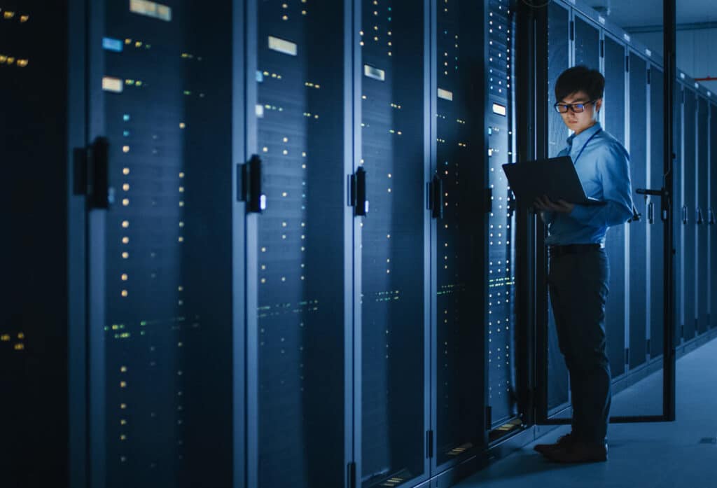 A male IT worker in a server room. Representing the Nations Benefits data breach class action.