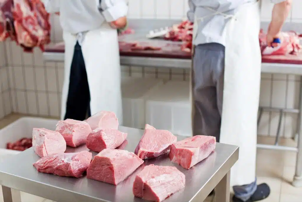 Close up of raw meat on a stainless steel table, representing the pork recall.