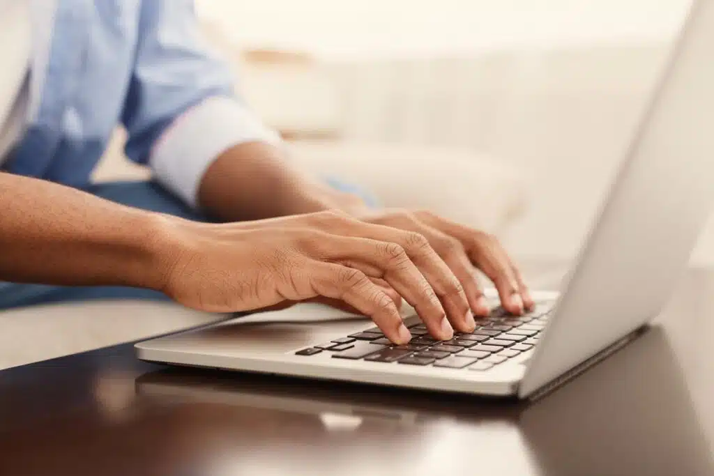 Close up of a males hands typing on a laptop, representing workers’ use of emails and time in meetings.