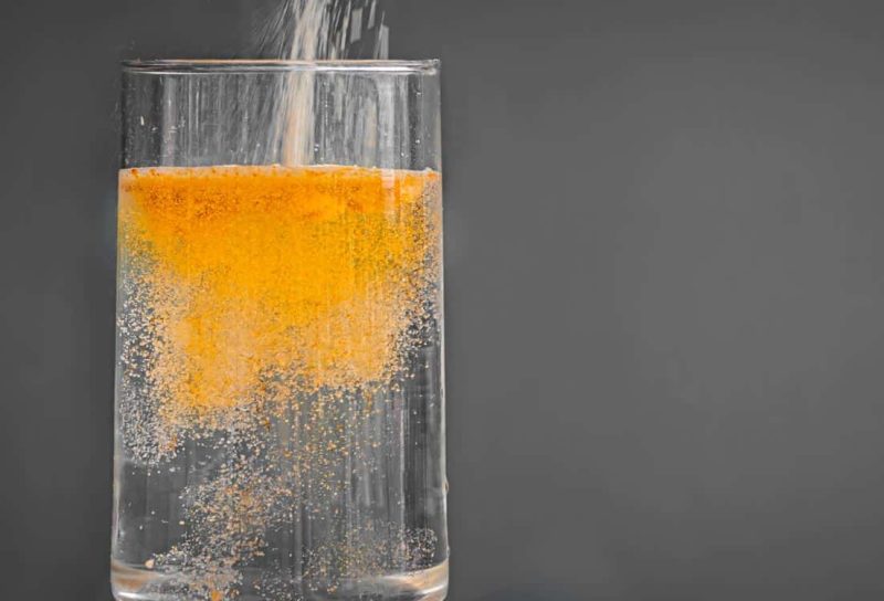 Powered orange drink mix being poured into a clear glass of water, representing the Lifeaid Beverage class action.