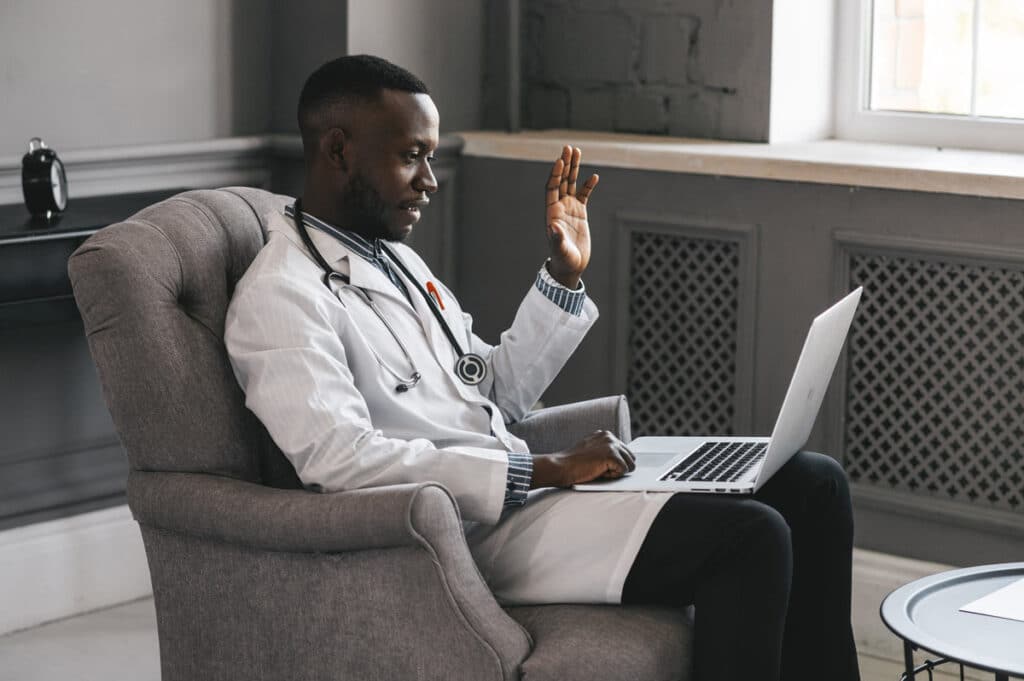 A doctor in an office on his laptop for a telehealth appointment with a patient, representing the Monument health information sharing class action.