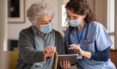 Senior lady and doctor looking at information on a tablet, representing the SuperCare Health data breach settlement.