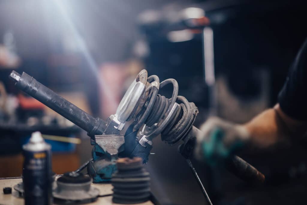 Close up of a mechanic working on an automotive shock absorber, representing the KYB and Hitachi Astemo shock absorbers class action lawsuit settlement.