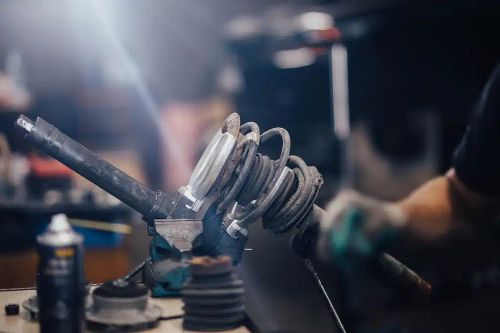 Close up of a mechanic working on an automotive shock absorber, representing the KYB and Hitachi Astemo shock absorbers class action lawsuit settlement.