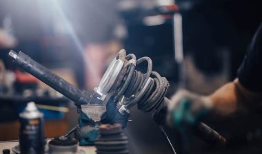 Close up of a mechanic working on an automotive shock absorber, representing the KYB and Hitachi Astemo shock absorbers settlement.