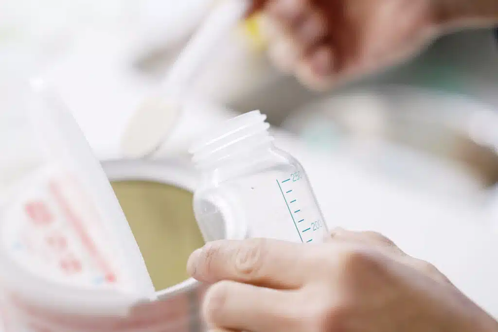 Close up of formula being scooped into a baby bottle.