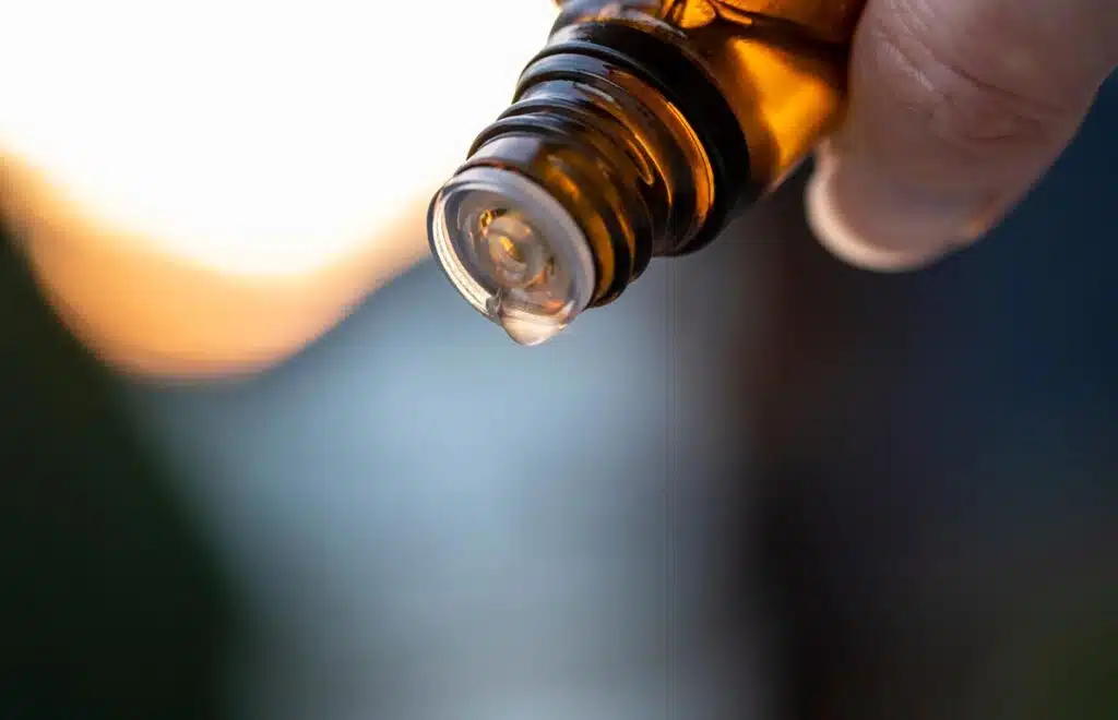 A close-up of a hand holding an essential oil bottle, representing the Young Living essential oils class action.