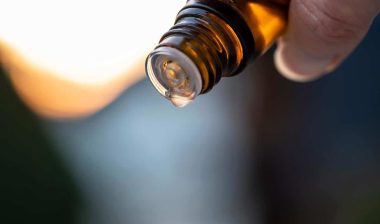 Close up of a hand holding an essential oil bottle.