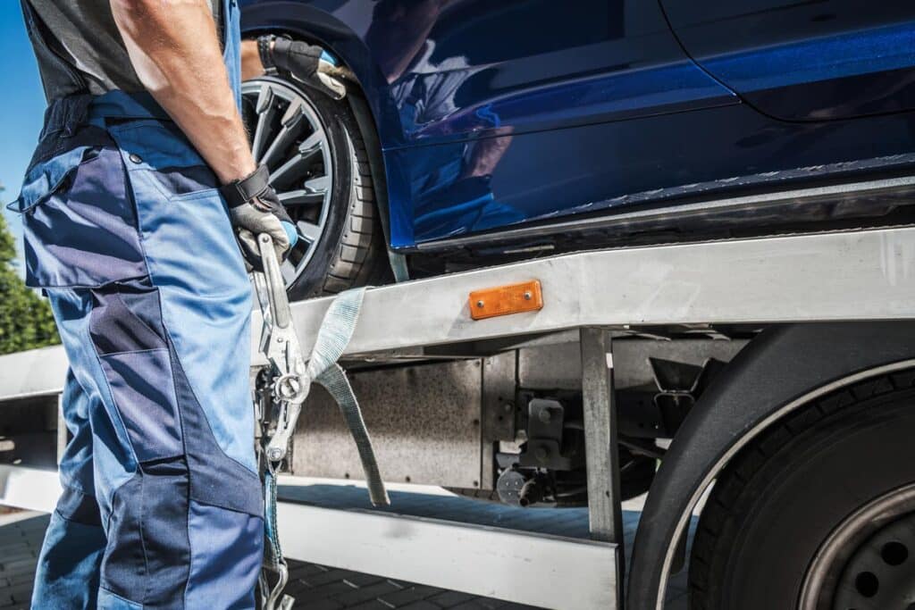 Close up of a car being secured to a tow truck, representing the Jefferson County, Kentucky, towing fees settlement.