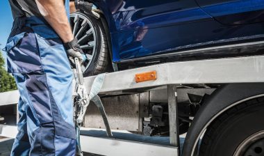 Close up of a car being secured to a tow truck, representing the Kentucky towing fees settlement.