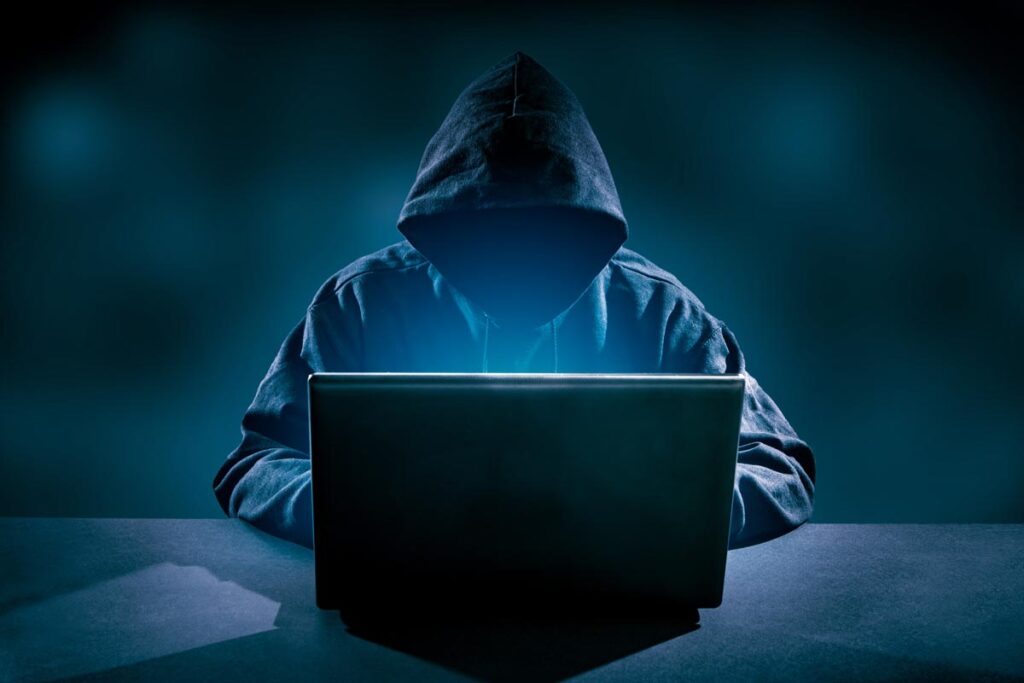 Hooded hacker using a laptop, representing the Microsoft hacking advisory.