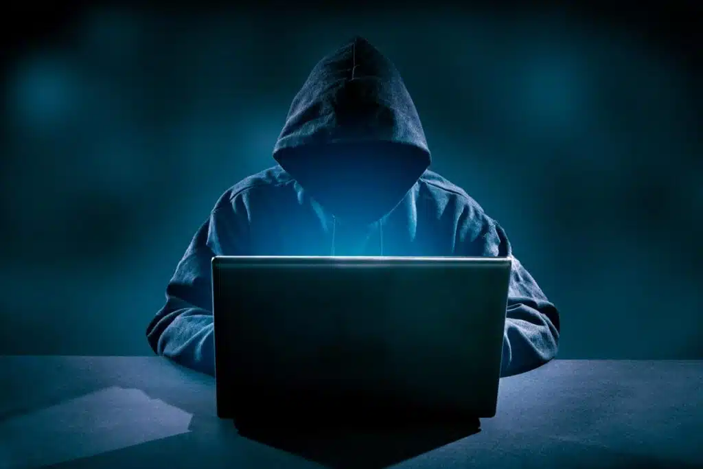 Hooded hacker using a laptop, representing the Microsoft hacking advisory.