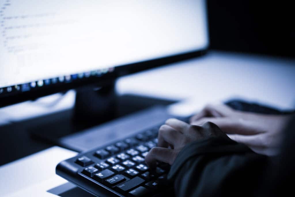 Hooded computer hacker stealing information with laptop, representing Russian cyber espionage.