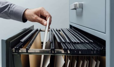 Close up of a hand searching through a file cabinet, representing the Connect Hearing settlement.