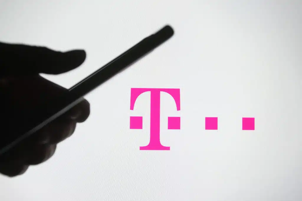 In this photo illustration a silhouette of a hand is seen holding a phone in front of T-mobile logo on a screen representing the T-Mobile data breach.