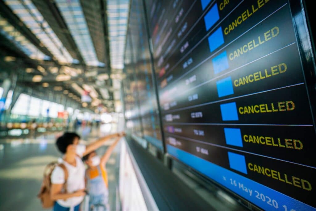 A woman and child look at flight status boards in an airport, representing the Turkish Airlines flight cancellations class action settlement.