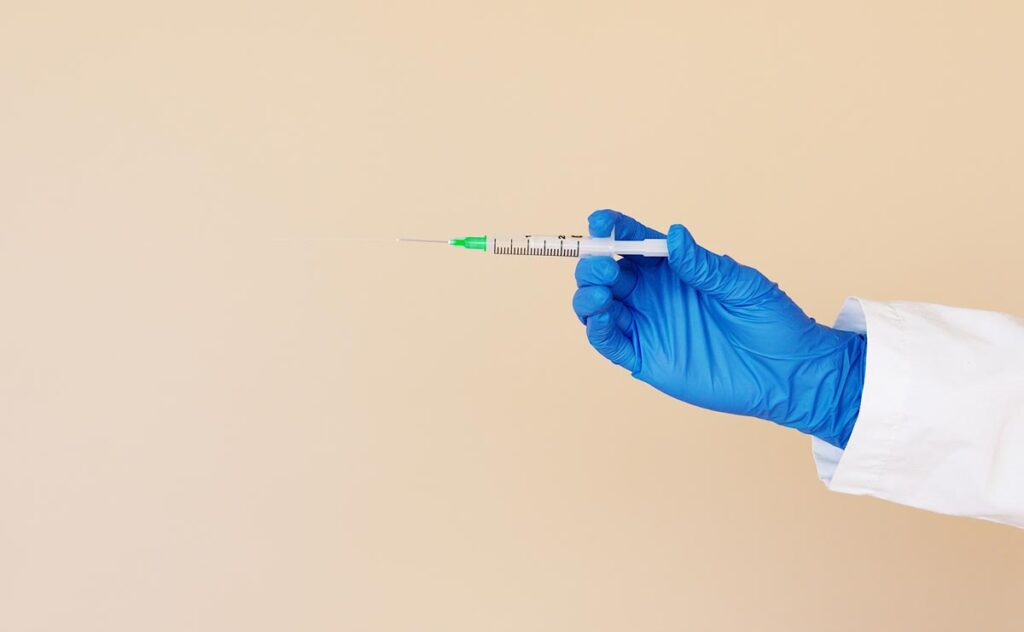 Close up of a medical professionals hand holding a medical syringe, representing off-brand Ozempic and Wegovy.