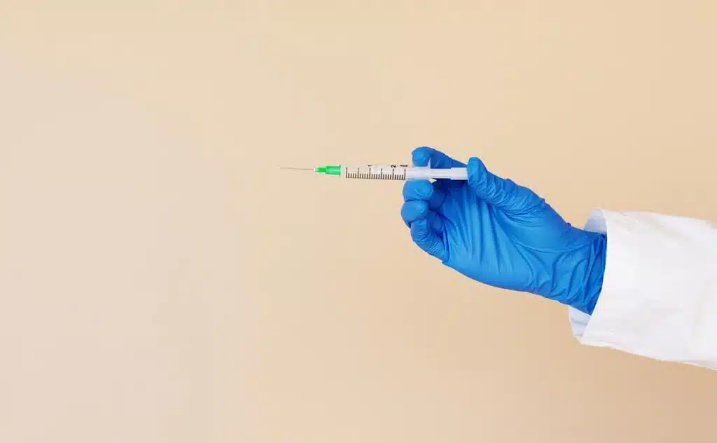 Close up of a medical professionals hand holding a medical syringe, representing off-brand Ozempic and Wegovy.