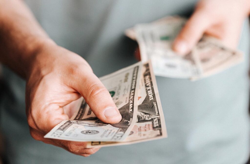Close up of a mans hands holding cash, representing recent class action rebates.
