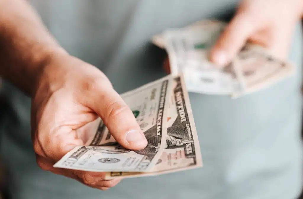 Close up of a mans hands holding cash, representing recent class action rebates.