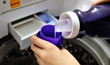 Close up of hand pouring laundry detergent into cup, representing the Woolite class action lawsuit.