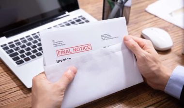 Close up of a persons hands opening a letter with a stamp that reads, Overdue, representing the Convergent Outsourcing settlement.
