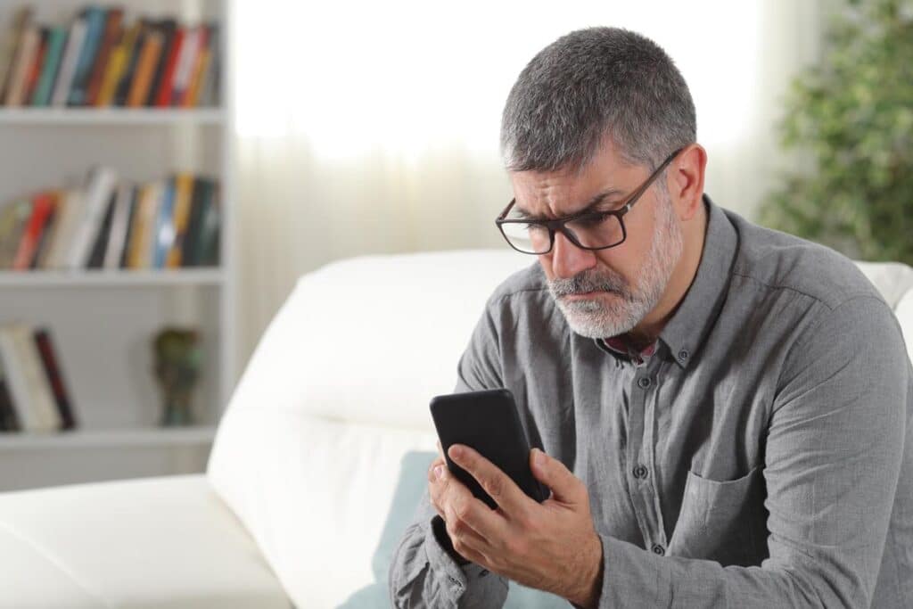 Irritated male looking at his smartphone, representing the New York & Company text messages class action.