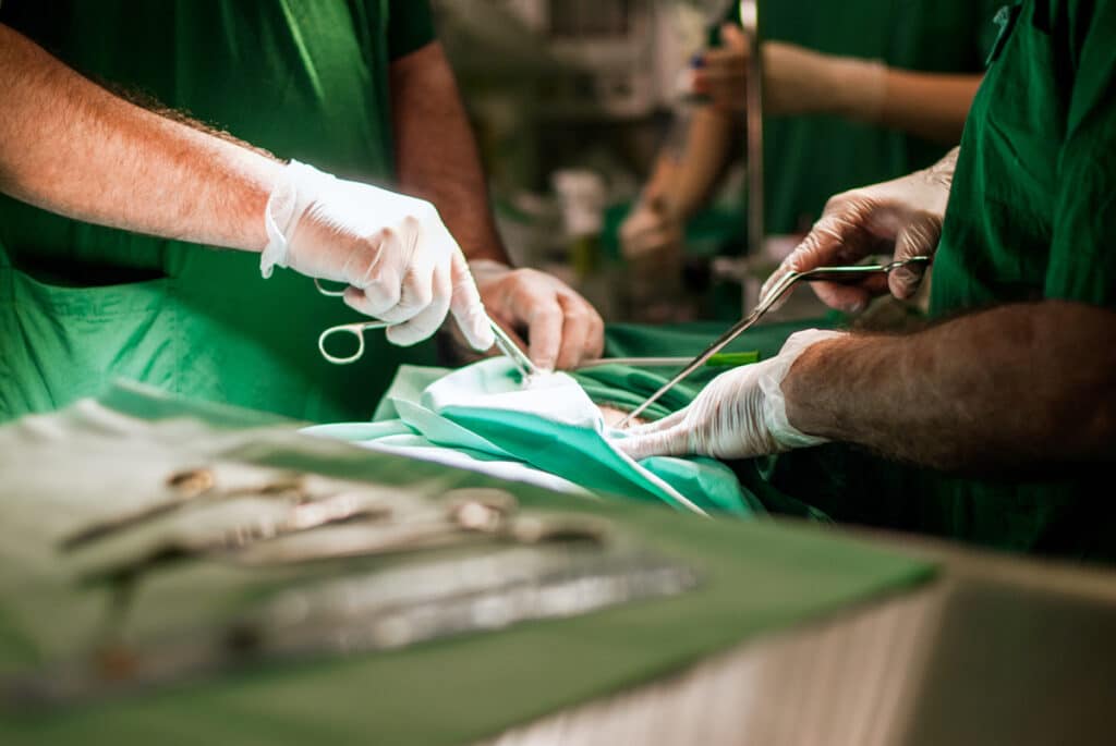 Close up of two suregons hands performing a surgery, representing the instrument sterilization class action lawsuit.